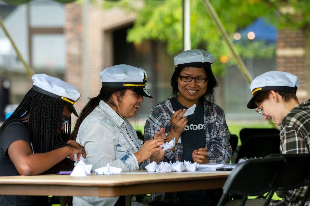 Image 1 of 4 Four students making paper boats
